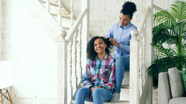 Zwei afrikanische amerikanische lockige Mädchen sistres machen Spaß lockige Frisur einander und haben Spaß zu Hause — Stockfoto