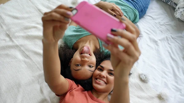 Κάτοψη του όμορφη μικτή φυλή αστεία φίλες κάνοντας πορτρέτο selfie στο κρεβάτι στο υπνοδωμάτιο στο σπίτι — Φωτογραφία Αρχείου