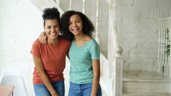 Porträt zweier wunderschöner afrikanisch-amerikanischer Mädchen, die zu Hause lachen und in die Kamera schauen — Stockfoto