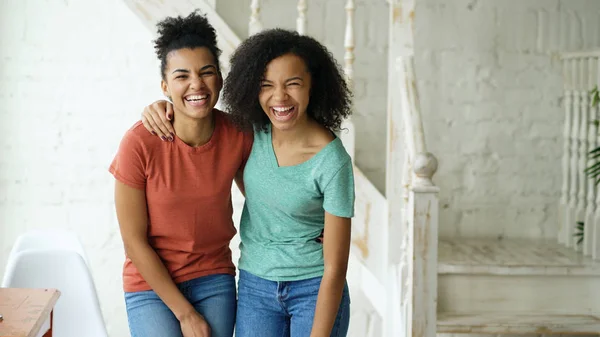 Retrato de duas lindas meninas afro-americanas rindo e olhando para a câmera em casa — Fotografia de Stock