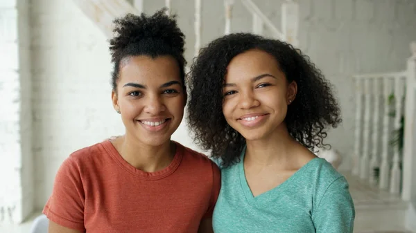Porträt zweier wunderschöner afrikanisch-amerikanischer Mädchen, die zu Hause lachen und in die Kamera schauen — Stockfoto