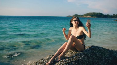 Mutlu kadın okyanus plaj smartphone kullanarak internet üzerinden arkadaşlarınızla sohbet