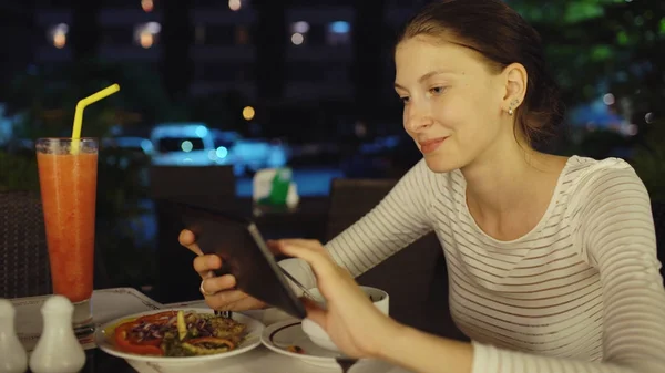 Smartphone kullanarak ve gece restoranda oturan mesajlaşma mutlu kadın — Stok fotoğraf