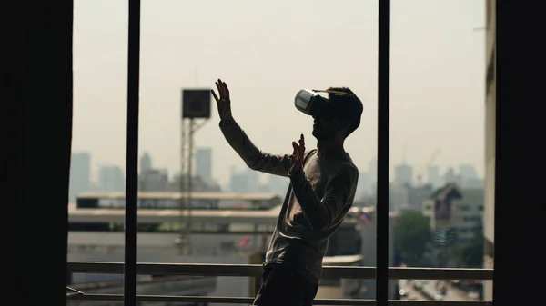 Silueta de hombre joven viendo la película en los auriculares VR y tener experiencia de realidad virtual en el balcón de la habitación de hotel — Foto de Stock