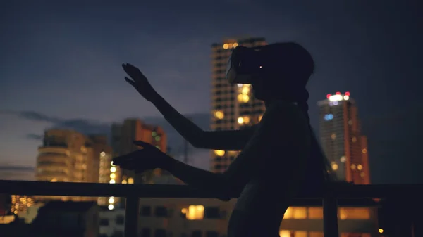 Jonge vrouw op dakterras met behulp van virtual reality headset en Vr ervaring bij nacht — Stockfoto