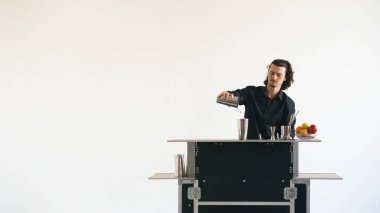 Beyaz arka plan üzerinde mobil bar masasında kokteyl sallayarak iş barmen adam
