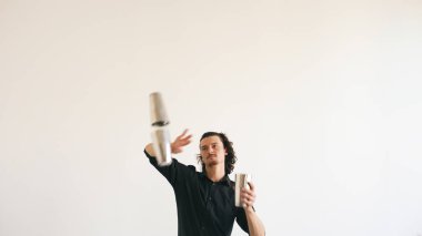 Şişe hokkabazlık ve beyaz arka plan üzerinde mobil bar masasında kokteyl sallayarak iş barmen adam