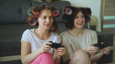 İki komik kadın gamepad ile konsol oyunları oynamak ve evde eğlenmek