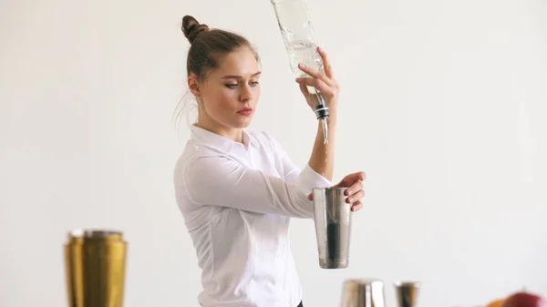Професійний бармен дівчина жонглює пляшки і трясе коктейль на мобільному барному столі на білому тлі — стокове фото
