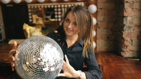 Gyönyörű fiatal nő, disco labdát jelentő és mosolyogva bent a stúdióban — Stock Fotó