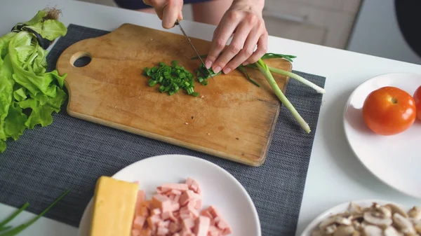 Pizza evde mutfakta ahşap tahta üzerinde yeşil soğan kesme kız closeup eller