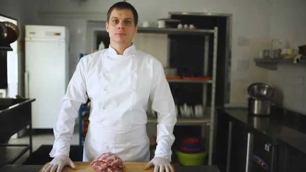 Professional chief cook posing before prepare steak dish at restaurant