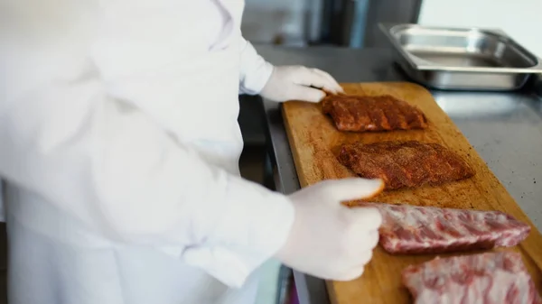 Primer plano del chef profesional hombre preparar costillas de carne con especias en la tabla de cortar en la cocina del restaurante — Foto de Stock