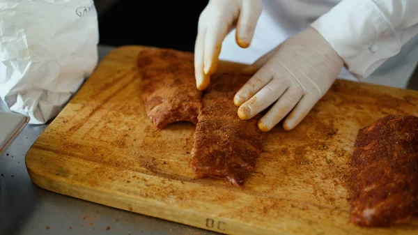 Close-up de chef profissional homem preparar costelas de carne com tempero na placa de corte na cozinha do restaurante — Fotografia de Stock