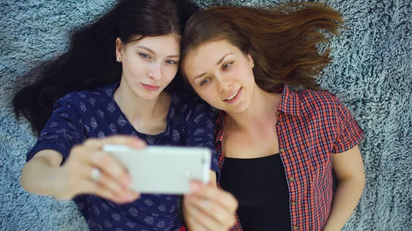 Widok z góry z dwóch ładne dziewczyny w piżamie podejmowania selfie portret na łóżko w sypialni w domu — Zdjęcie stockowe