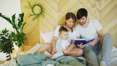üç sabah yatakta yatan sevgi dolu bir aile. Aile sarılma ve kitap okuma