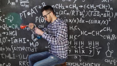 Genç bilim adamı adam olun kimyasal deney Laboratuvarı ve Matematiksel denklemler oda duvar