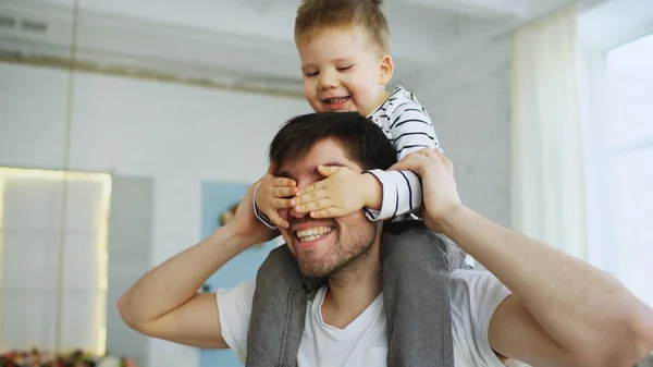 Feliz padre llevando a su hijo sonriente en el cuello en el dormitorio — Foto de Stock