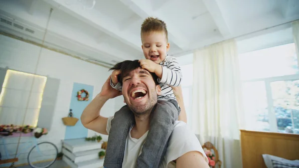 Feliz padre llevando a su hijo sonriente en el cuello y haciendo selfie en el teléfono inteligente en el dormitorio — Foto de Stock