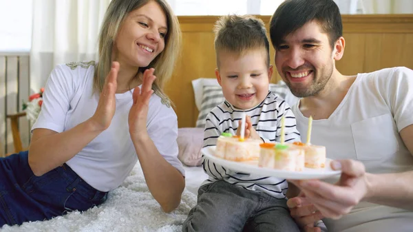 Sonriente familia celebrando su hijo cumpleaños juntos antes de soplar velas en la torta — Foto de Stock