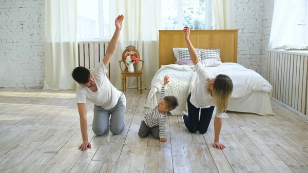 Familia haciendo ejercicios de gimnasia en el dormitorio en el hogar - educación para la vida saludable — Foto de Stock