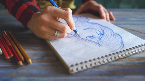 Gros plan de croquis de peinture à la main féminine sur carnet de papier avec crayons. Femme artiste au travail — Photo