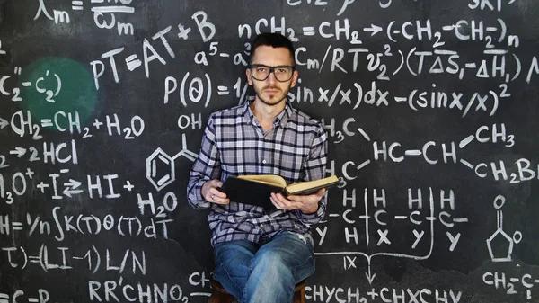 stock image Young scientist man read book in chemical and mathematical equations wall room interior