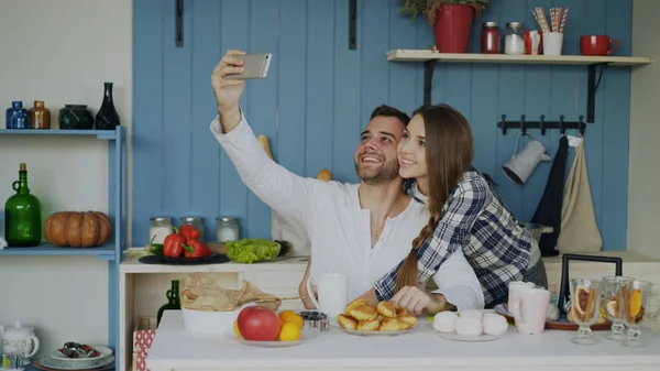 Молода щаслива пара бере портрет селфі, снідаючи на кухні вдома — стокове фото