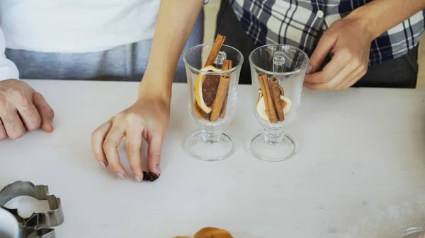 Primer plano de un par de manos mezclando los condimentos en una copa de vino caliente en la cocina en casa — Foto de Stock