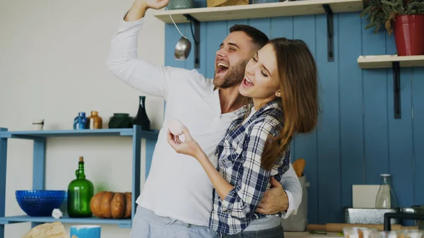 Pareja alegre divertirse bailando y cantando en la cocina en casa por la mañana — Foto de Stock