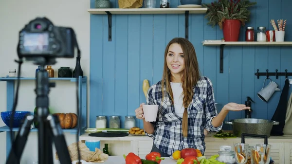 Молодая привлекательная женщина записывает видеоблог о кулинарии на камеру на кухне — стоковое фото
