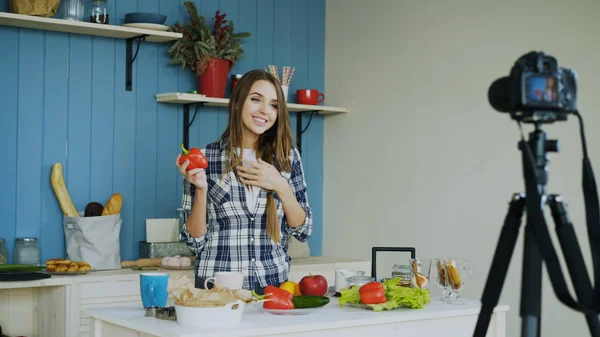 Веселая привлекательная женщина запись видео блог о вегетарианской здоровой пищи на dslr камеры на кухне дома — стоковое фото