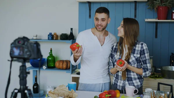 Alegre pareja atractiva grabación video comida blog acerca de cocinar en dslr cámara en la cocina en casa — Foto de Stock