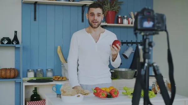 Bel homme gai enregistrement vidéo blog sur végétarien alimentation saine sur caméra dslr dans la cuisine à la maison — Photo