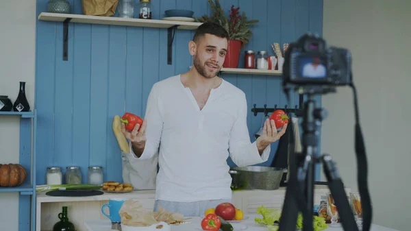 Bel homme gai enregistrement vidéo blog sur végétarien alimentation saine sur caméra dslr dans la cuisine à la maison — Photo