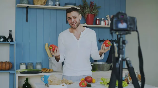 Beau gai homme enregistrement vidéo blog alimentaire sur la cuisine sur caméra dslr dans la cuisine à la maison — Photo