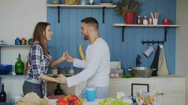 Веселая и привлекательная молодая пара влюбленных танцует вместе латинский танец на кухне дома в праздничные дни — стоковое фото