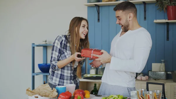 Χαρούμενη γυναίκα έκπληξη του boylfriend με δώρο γενεθλίων στο σπίτι στην κουζίνα ενώ ο ίδιος μαγείρεμα πρωινό — Φωτογραφία Αρχείου