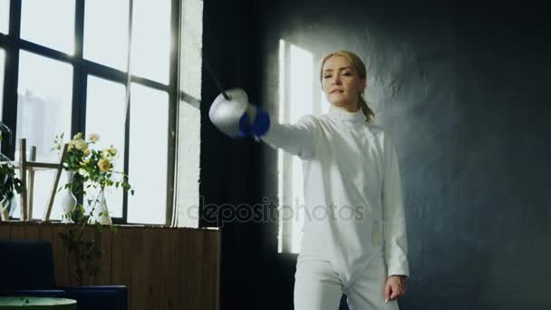 Young concentrated fencer woman training fencing exercise in studio indoors — Stock Video