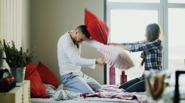 Mutlu ve sevgi dolu bir genç çift yatakta evde yastıklar sabahları mücadele.
