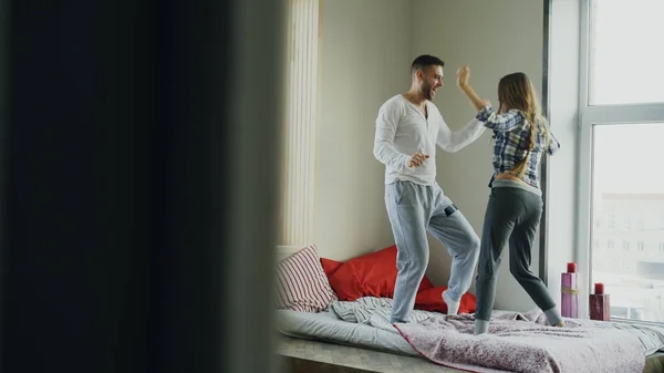 Junges schönes und liebevolles Paar, das morgens zu Hause Rocknroll-Tanz auf dem Bett tanzt — Stockfoto