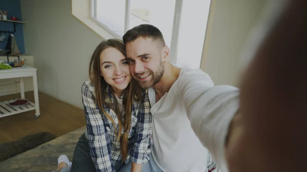 POV tiro de casal bonito e amoroso conversando on-line vídeo chat segurando smartphone e conversando com amigos sentados na cama em casa pela manhã — Fotografia de Stock