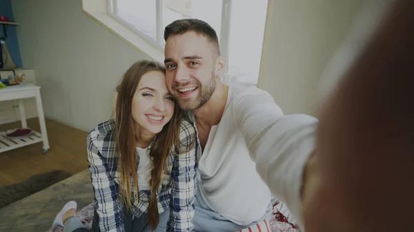 POV shot of cute and loving couple talking online video chat holding smartphone and chatting to friends sitting in bed at home in the morning — Stock Photo, Image