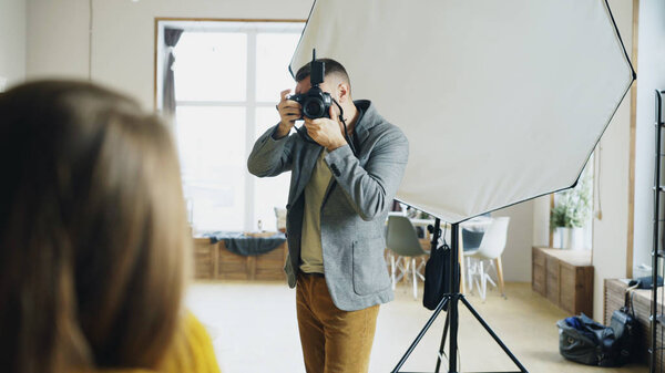 Профессиональный фотограф фотографирует модель на цифровую камеру, работающую в фотостудии
