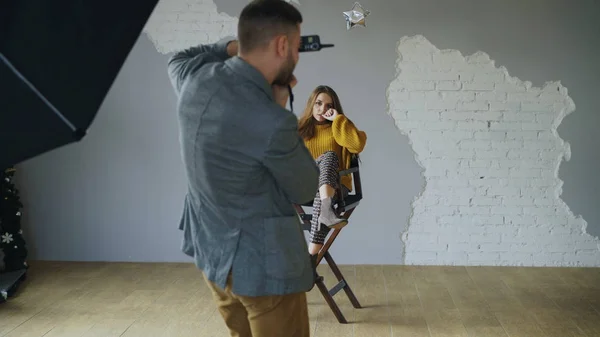 Giovane bella donna modello in posa per il fotografo mentre sta scattando con una macchina fotografica digitale in studio fotografico al chiuso — Foto Stock