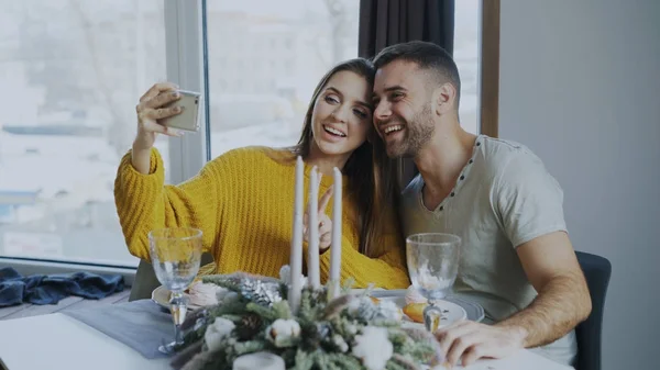 Feliz casal sorrindo almoçando e tirando retrato selfie com smartphone no café dentro de casa — Fotografia de Stock