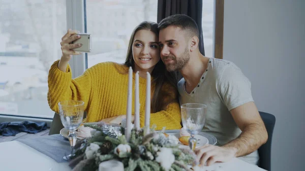 Glückliches lächelndes Paar beim Mittagessen und Selfie-Porträt mit Smartphone im Café drinnen — Stockfoto