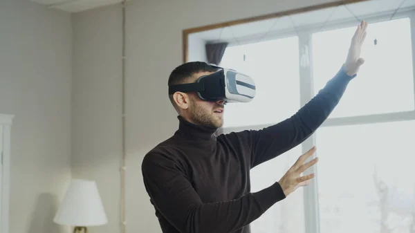 Возбужденный человек с гарнитурой виртуальной реальности, играющий 360 видеоигр дома — стоковое фото