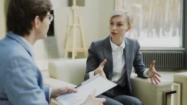 Zakenvrouw praten en duscussing Financiën bedrijfsgegevens met mannelijke zakenpartner zittend op fauteuil in moderne kantoren — Stockvideo