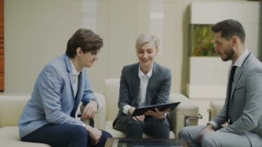 Modern ofis koltukta oturan erkek iş meslektaşları ile atış işkadını dijital tablet duscussing ile kaydırma